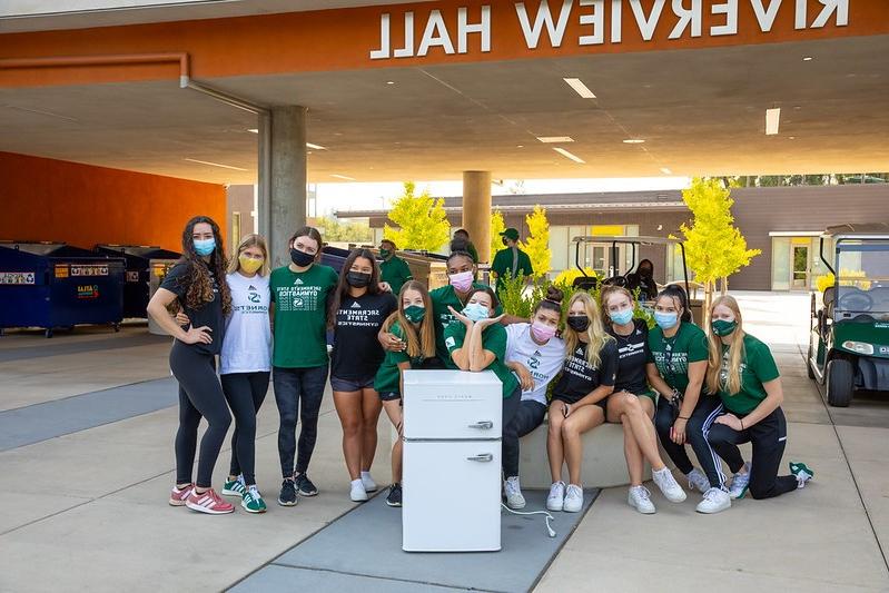 Photo of students standing around a mini fridge on move-in day